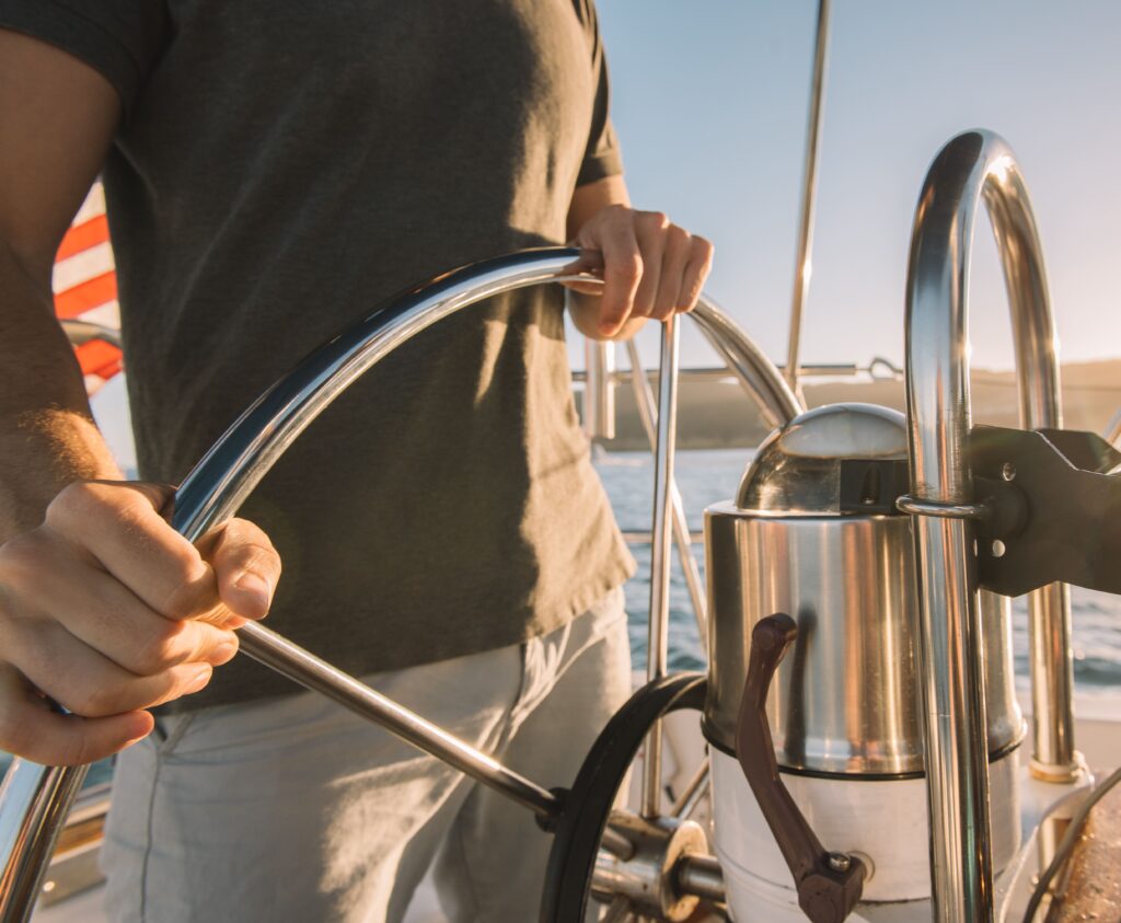Man driving sailboat behind the wheel.